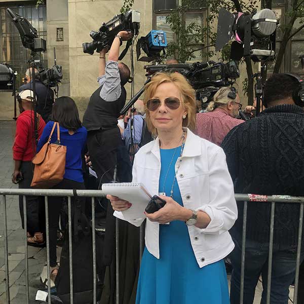Sarah Wallace on a live shot with a Channel 4 microphone, cameras and lights behind her.
