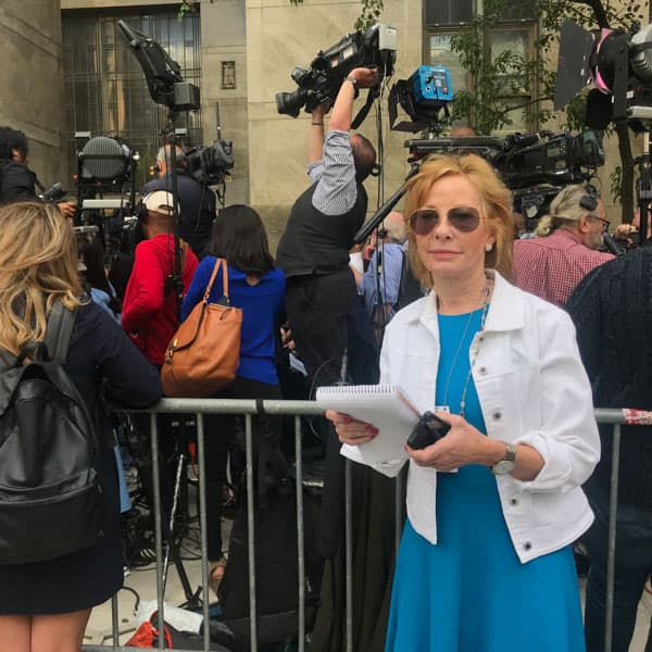 Sarah Wallace on assignment in a media scrum, notepad in hand.